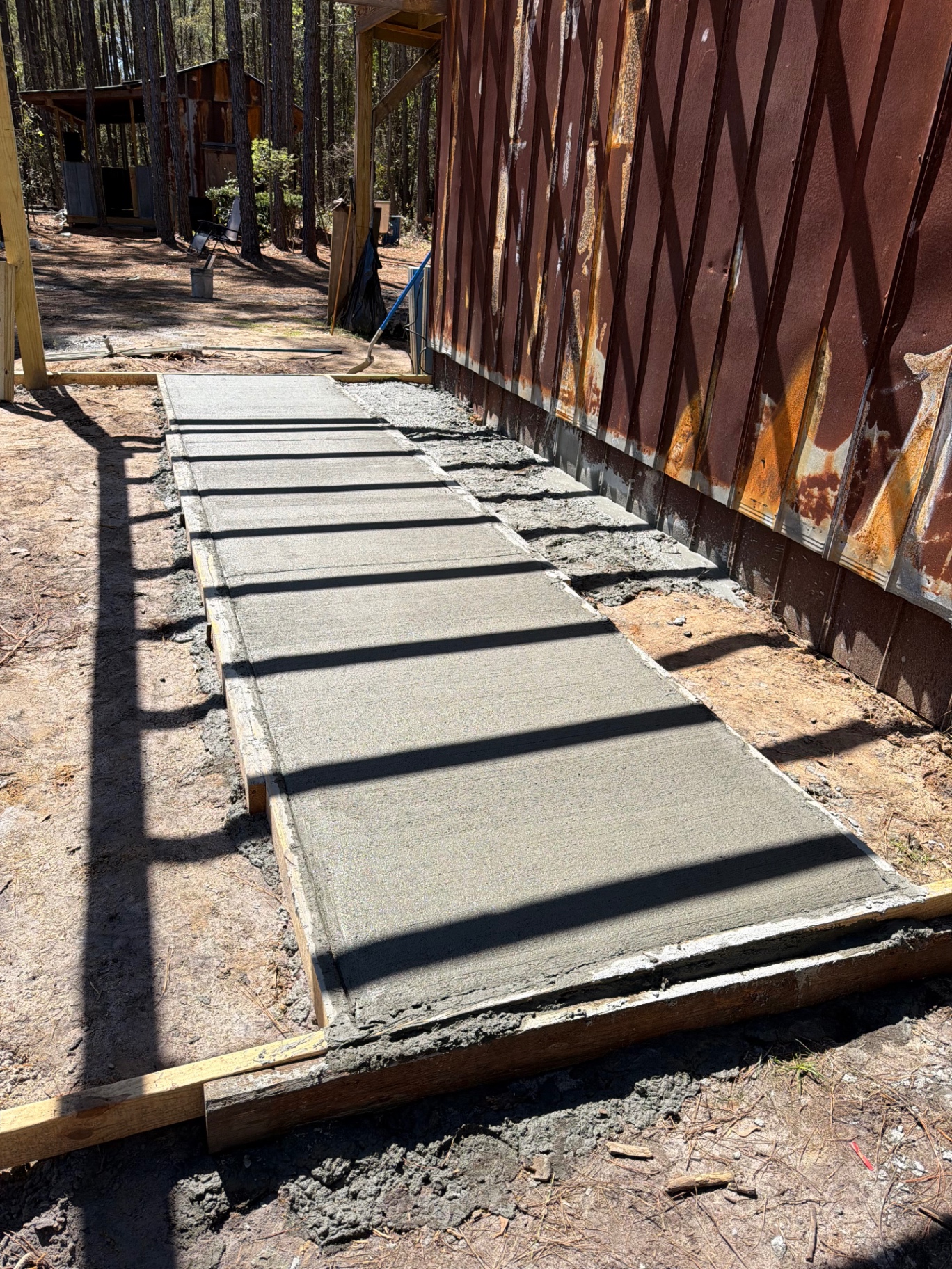Freshly poured concrete walkway formed beside a building