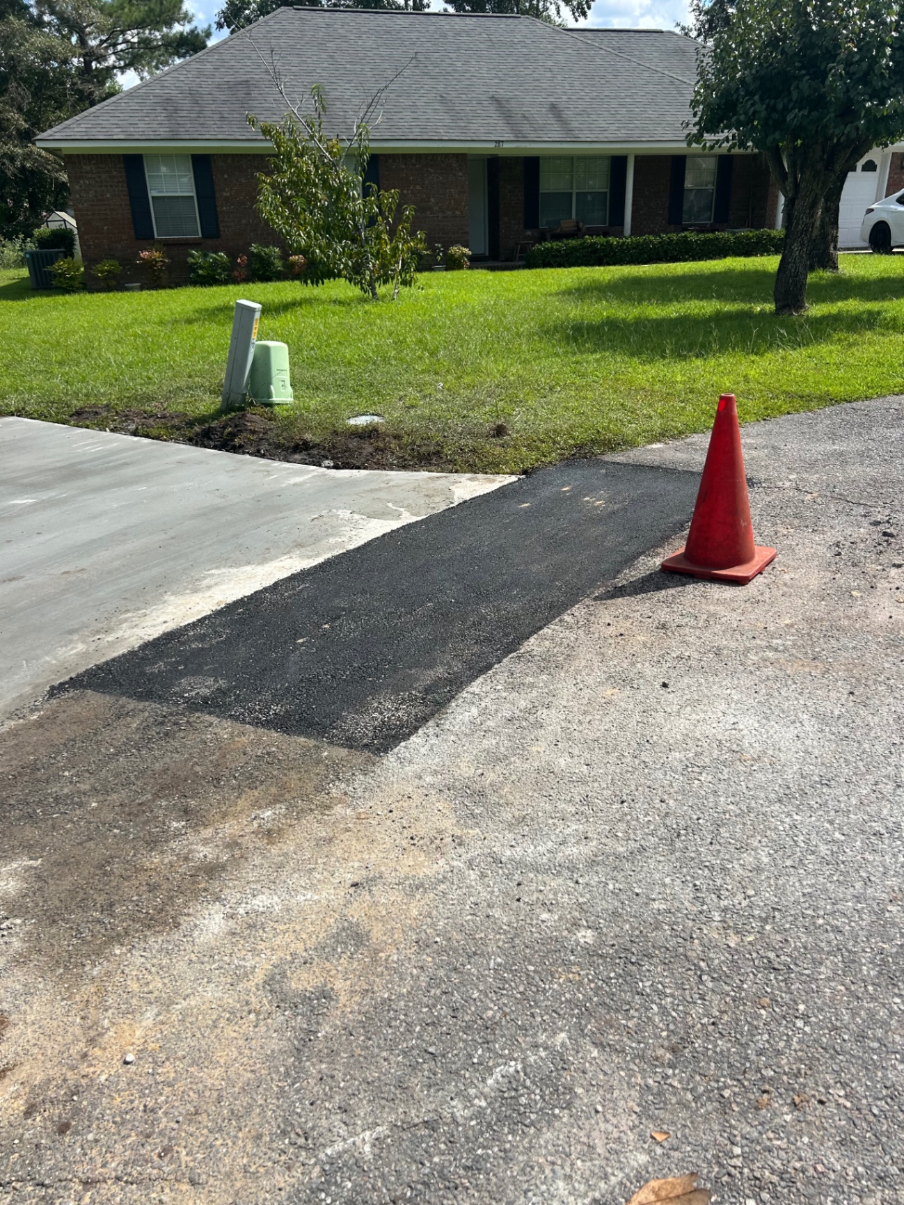 Asphalt tie-in patch where new concrete meets the road